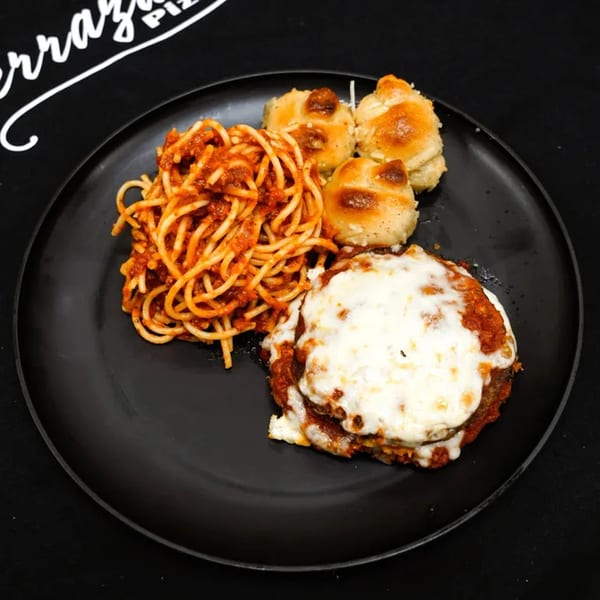 A black plate with spaghetti, three garlic knots, and a cheesy chicken parmesan from Verrazano Pizza.