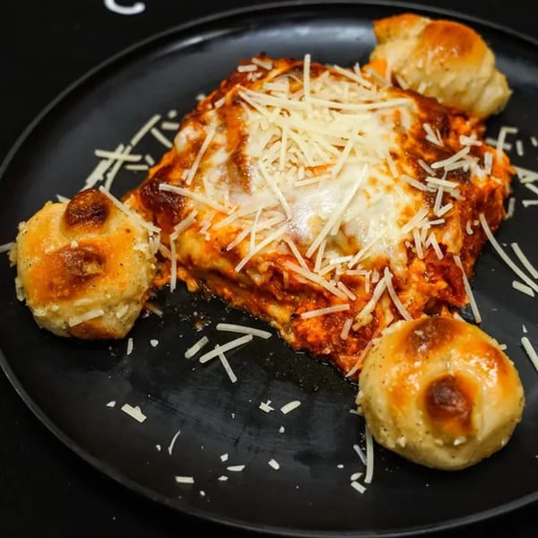 Verrazano Pizza's lasagna with melted cheese and tomato sauce, served with three garlic knots.